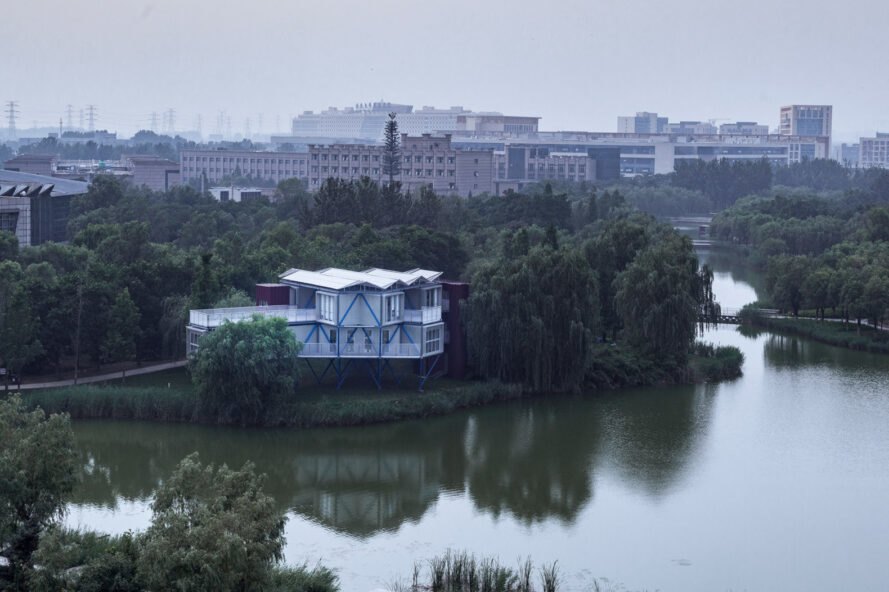 aerial view of large raised white building beside a lake