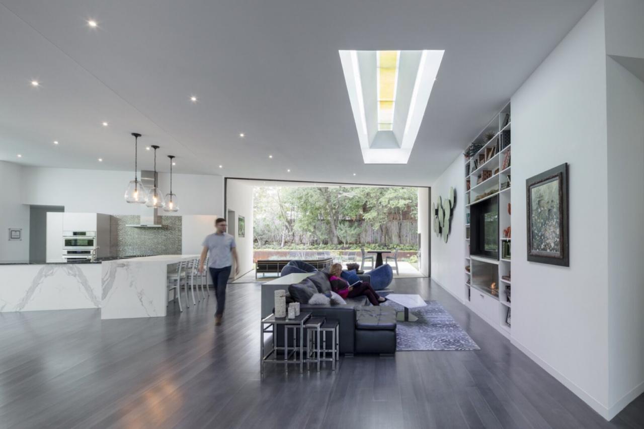 open-plan living area with gray sofa, white kitchen and skylights