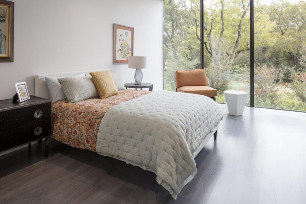 white and coral bed in room with glass wall
