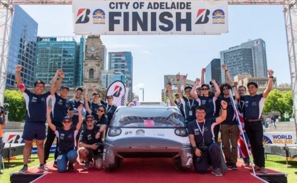 team of students near a white electric car