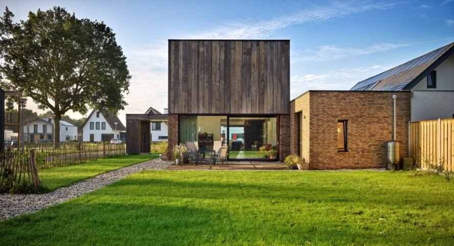 wood and brick home with glass wall and outdoor patio