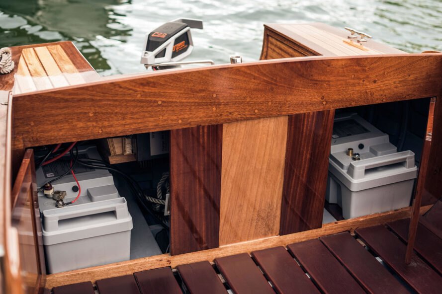 a wooden boat with electrical motor components in a compartment towards the back of the boat