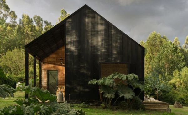 black gabled home with small, light wood porch